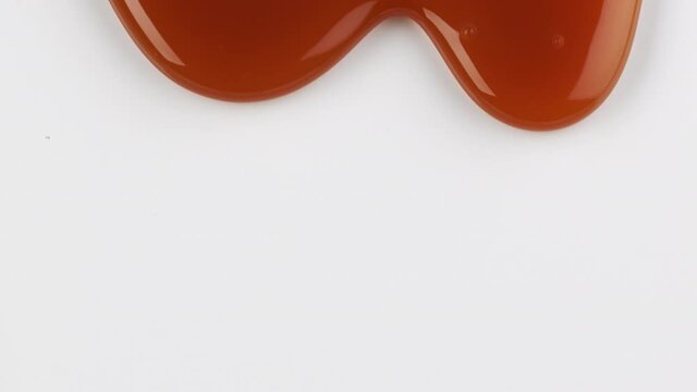close up of flowing melted caramel sauce macro on white background