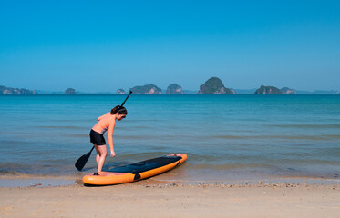 young sporty woman playing stand-up paddle board on the blue sea in sunny day of summer vacation