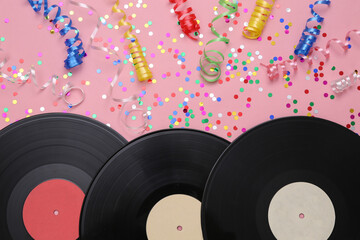 Vinyl records and colored streamer with confetti on a pink background. Music day