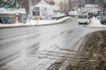 Slush.Asphalt road covered with melting dirty snow and mud on an early spring day.Road is not cleared of snow.Spring thaw.Snow melting.Large muddy puddle in the middle of the highway.