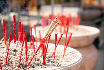 Red burning incense sticks in pot with white smoke. Selective focus.
Pray, meditation, Chinese tradition concept.