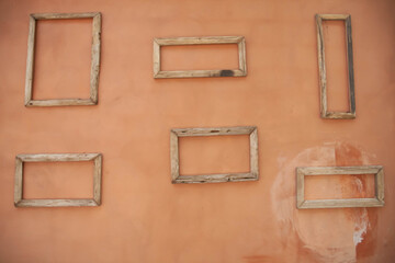 Wooden empty rectangle-shape frames on dirty orange wall.