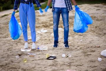 Young man and woman picking up trash outdoor.
