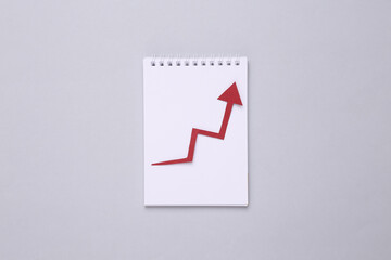 Notepad with growth arrow on gray background. Business concept