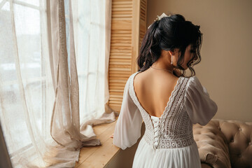 Fototapeta premium Wife at the photo session in studio. Married bride celebrate engagement. Procreation romantic amazing woman indoor, copy space. Prepating for wedding day corset dressing fees, fasten dress