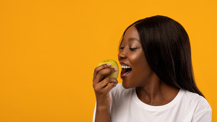 Healthy black lady eating green apple, panorama with copy space