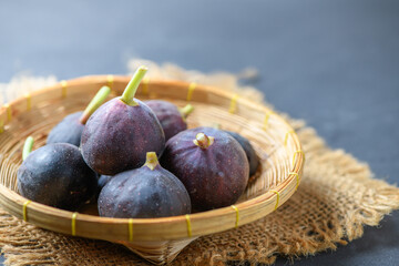 Fresh ripe figs in bamboo basket on dark table. Healthy mediterranean fig fruit.