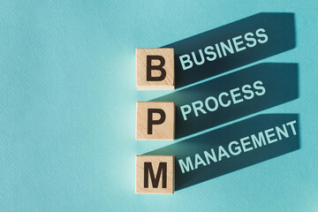 Wooden cubes building word BPM (abbreviation of Business process managemen) on light blue background.