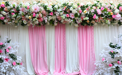A multi-colored flower arrangement on a white and pink fabric background in the wedding ceremony.