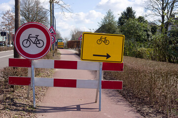 Road closed with roadblock for roadworks and a detour sign for cyclists 