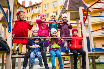 Obraz na płótnie Canvas Cheerful kids at outdoor playground in early spring