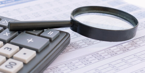 Calculator with a magnifying glass on a financial background