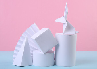 Easter minimalistic composition of origami bunny and geometric shapes on blue pink pastel background. Concept art