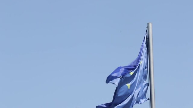 Video of European union flag, stars and blue color on the blue sky. Close-up of flag moving during the wind, windy weather in Tbilisi, Georgia.