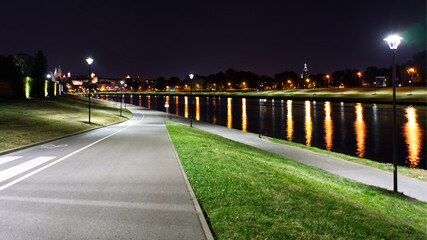 Night view on Wisla river in Cracow. City lights reflected in water, city mood, though empty during pandemic. © EvoraArt