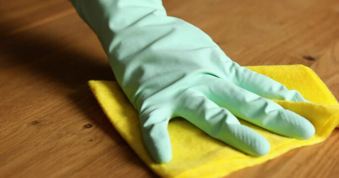 Unrecognizable female in latex gloves with microfiber rag cleaning the wooden table surface , desk at home, woman wife do daily house cleaning routine.