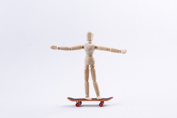 Wooden puppet is riding a skateboard.