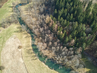 Aerial shot of a turquoise river flowing through a conifer forest. Aerial shot of a meandering river.