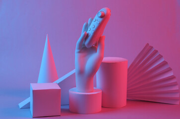 Hand holding modern joystick, Geometric shapes in red-blue gradient neon light. Creative showcase....