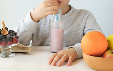 Child drinking berry yogurt at the table, healthy food for children