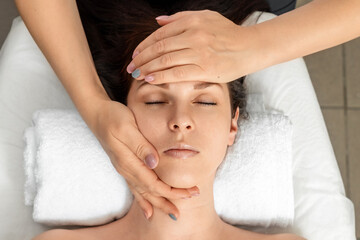 Facial massage close-up. Young, beautiful girl at spa procedures. Skin care, oriental massage treatments, beauty treatments.