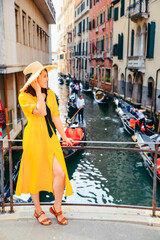 Fototapeta na wymiar woman in yellow sundress at bridge with view at venice canal