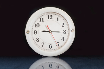 Round clock on glass table with reflection