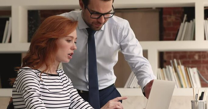 Female trainee ask to male mentor about corporate software, receive helpful information during meeting in office. Colleagues share skill and thoughts working on collaborative online project use laptop