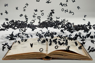 Letters of the alphabet in levitation in the air over the open book
