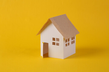 Fototapeta na wymiar Mini paper house model on yellow background