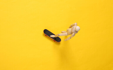The puppet is riding a skateboard. Yellow background. Top view