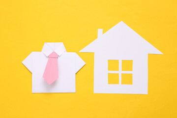 Paper cut house and origami shirt on yellow background