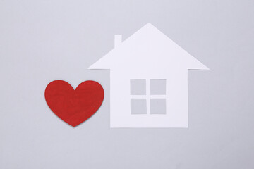 Mini paper house figurine and heart on gray background. Flat lay