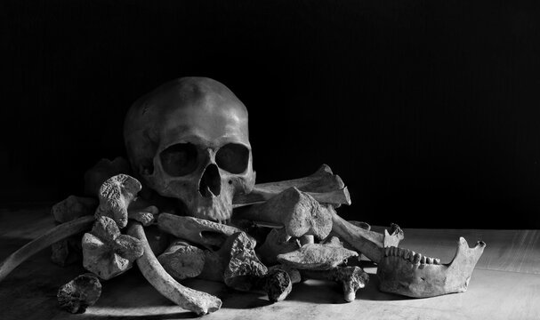 The old skull put on pile bone on wooden plank and black background