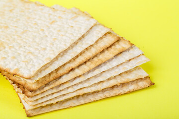 Square matzo several sheets one on top of the other on a yellow background.