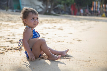 adorable toddler girl playing on sandy beach of tropical island