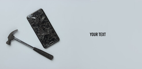 Smartphone with broken glass screen and hammer on a white background. Top view. Copy space