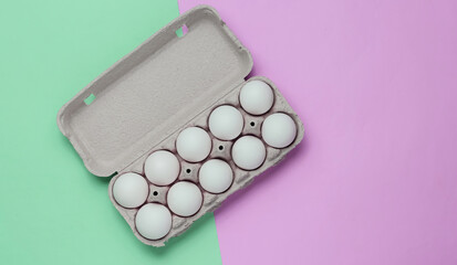 Cardboard tray with eggs on pink green pastel background. Minimalism cooking concept. Top view.