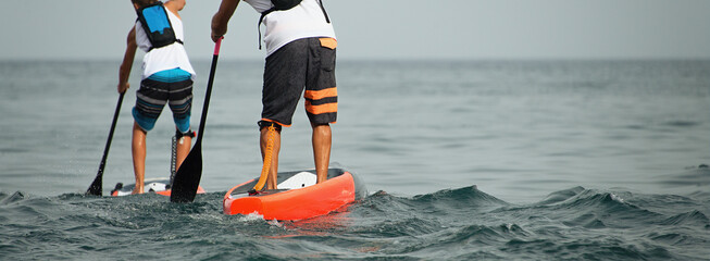 Stand up paddle group on the sea, men friends sail on a sup boards - obrazy, fototapety, plakaty