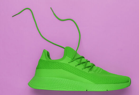 Green Sport Running Shoe With Untied Laces On Pink Background. Top View