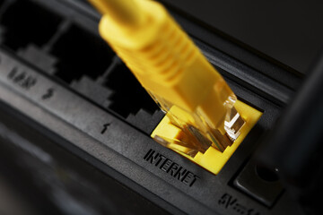A yellow patch cord is inserted into the Wi-Fi port of the router to access the Internet.