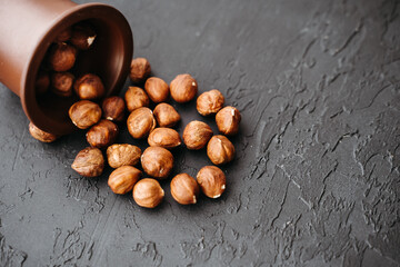 hazelnuts in a brown bowl on a black background