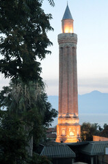 Asian city mosque in sunset with a very high minaret and pine near