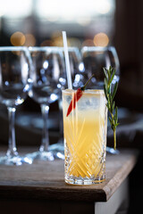 Yellow coctail with chilie on corner of wooden table