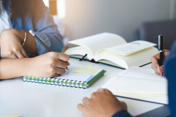 Close up hands of university student studying in class and taking note in notebook.