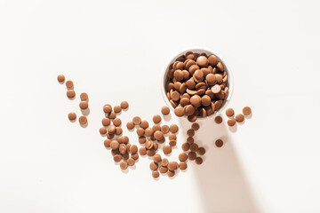 Chocolate callets in a white disposable cup on a white background. top view close-up. Flat lay....