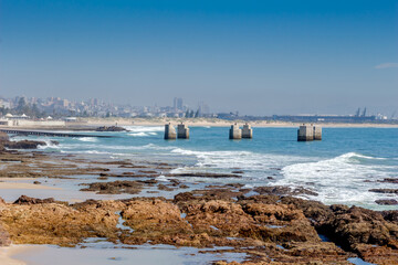Old pier at Humewood Beach in Port Elizabeth with city buildings in background