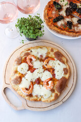 Pizza on a wooden board with mozzarella, mini arugula.