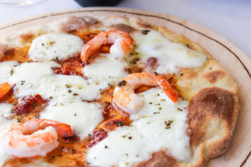 Pizza on a wooden board with mozzarella, mini arugula.