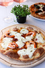 Pizza on a wooden board with mozzarella, mini arugula.